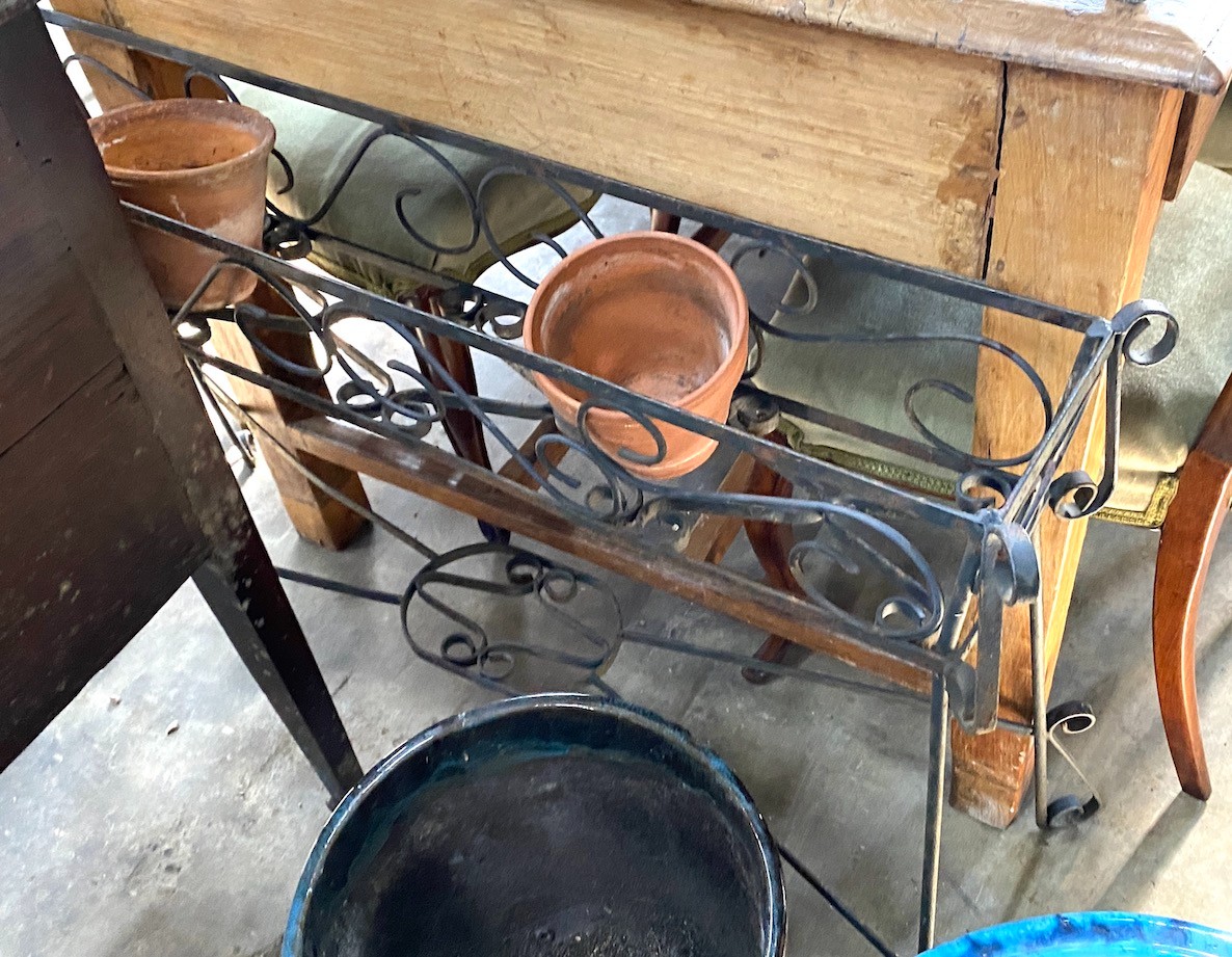 Two wrought iron slatted garden chairs, a circular table and a wrought iron pot stand